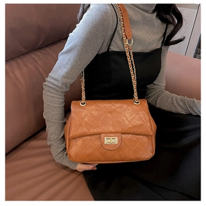 Macro detail of brown quilted leather texture and gold metal twist-lock on shoulder bag