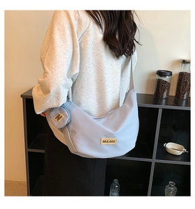 Détail du sac demi-lune bleu clair avec logo et petit porte-monnaie rond assorti