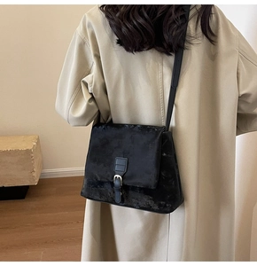 Rear view of a black frosted tote bag with metal buckle detail and long shoulder strap