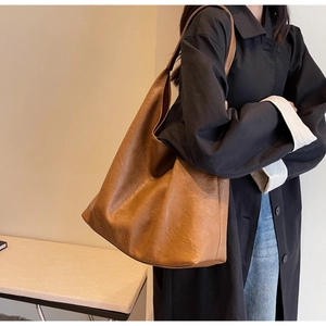 Détail d'un grand sac hobo marron avec texture plissée douce sur la bandoulière