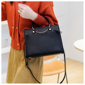 Modern black pebbled leather crossbody bag with minimalist gold metal ring handles