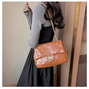 Detailed close-up of brown quilted leather texture and gold-tone metal twist lock closure