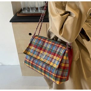 Detail of multi-color plaid tote bag with silver MR logo and chain strap on trench coat