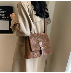 Detail view of the vintage brown faux leather texture and buckle strap on tote bag