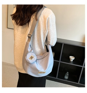 Détail d'un sac demi-lune bleu clair avec mini pochette et large bandoulière réglable