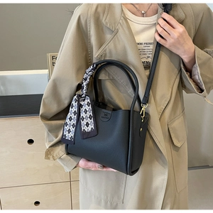 Detail of black lychee leather bucket bag with logo and check pattern scarf handle