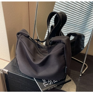 Detailed view of black canvas crescent bag with thick strap on a wooden desk with shadows