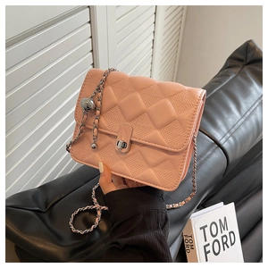 Dettaglio borsa in pelle rosa trapuntata con chiusura dorata e tracolla a catena