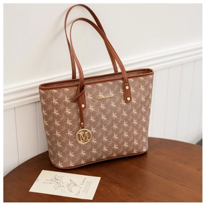 Gros plan d'un sac cabas marron avec motif pégase et pendentif en métal doré lettre M