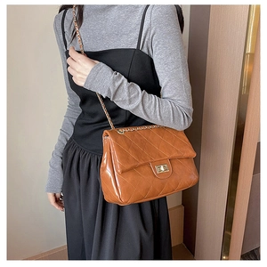Detail of caramel quilted leather shoulder bag with metallic chain and gold-tone twist lock