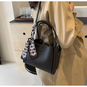 Close-up of black lychee leather bucket bag with decorative checkered silk scarf detail