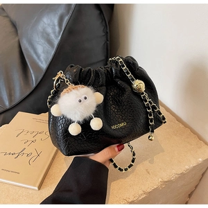 Detail of black pleated drawstring bag with gold chain strap and fluffy eye charm