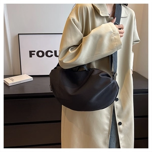 Close-up of black crescent nylon shoulder bag featuring an adjustable strap and side label
