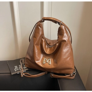 Detail of brown large tote bag featuring pleated PU leather and metallic M logo