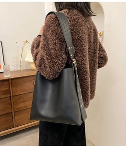 Vue détaillée d'un sac seau en cuir noir avec bandoulière large et boucle en métal