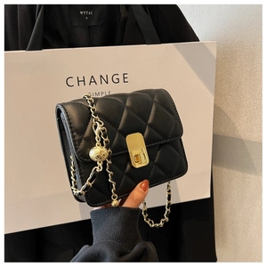 Detail of quilted black leather mini bag featuring gold hardware and ball chain detail