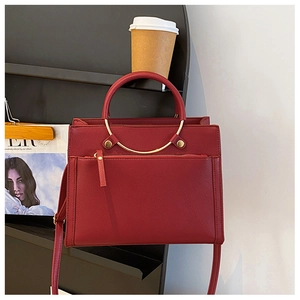 Detail of red leather bridal handbag with golden ring handle on a black shelf