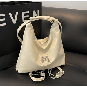 Detail of cream leather tote bag with silver M logo and chain shoulder straps