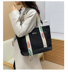 Détail du sac cabas en toile noire avec broderie et bandoulière tissée à fleurs colorées