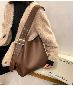 Détail de la bandoulière large réglable avec œillets dorés sur un sac seau marron