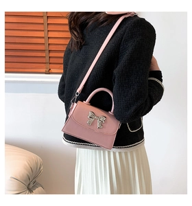 Pink leather handbag with silver bow detail shown on a model in a stylish outfit