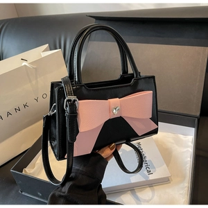 Detail of black PU leather handbag with large pink bow and heart-shaped rhinestone