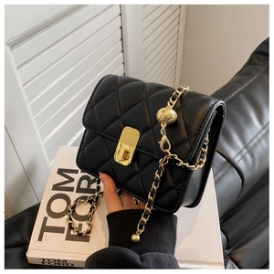 Detail of black quilted leather bag with gold chain strap and metal ball decoration
