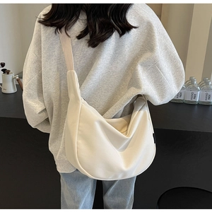 Close-up of off-white corduroy crescent bag showing texture and wide strap on model