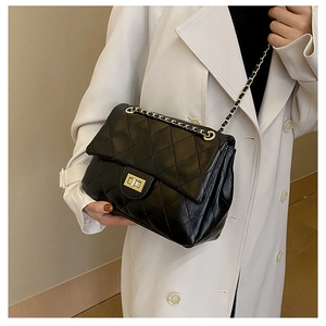 Detail of classic black quilted chain bag with gold twist lock on a crossbody square bag