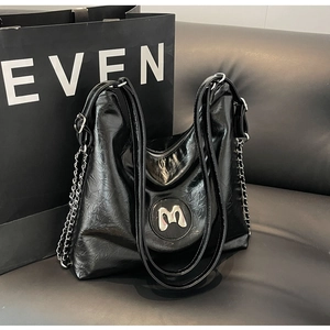 Detail of glossy wrinkled leather tote with silver metal chain and round M logo