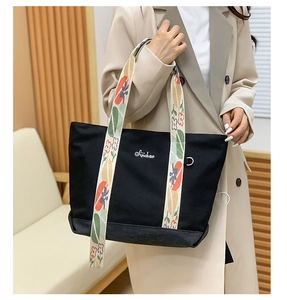 Détail du sac cabas en toile avec bandoulière tissée fleurie et logo brodé sur le côté