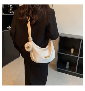 Détail d'un sac hobo en nylon blanc avec bandoulière large et mini pochette ronde