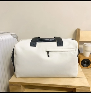 Détail du sac de voyage blanc en tissu Oxford avec poignées noires et grande poche zippée