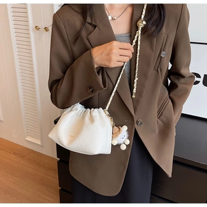 Close-up of white ruched cloud bag with chain strap and cute plush sheep charm detail