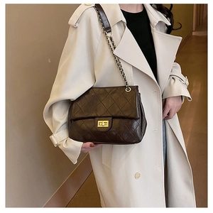 Detail of dark brown quilted crossbody bag featuring golden metal lock and chain strap