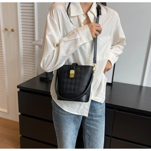 Détail d'un sac seau en cuir matelassé noir avec fermoir doré et bandoulière réglable