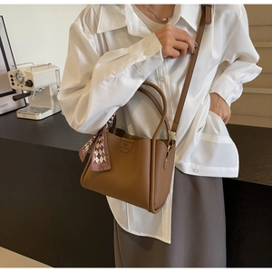 Detail of brown litchi pattern leather bucket bag with decorative diamond check scarf