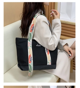 Détail du sac cabas en toile noire avec logo et bandoulière fleurie brodée