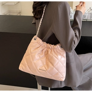 Detail of pink quilted bucket bag with chain strap and metallic logo on soft leather