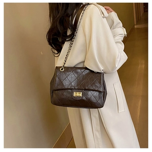 Detail showing the quilted chain bag in coffee brown worn with an autumn trench coat