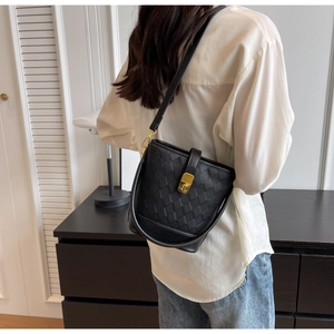 Détail du sac seau noir avec texture géométrique matelassée et fermoir pivotant doré