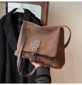Close-up of vintage brown leather tote bag with retro buckle and distressed texture