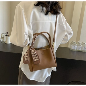 Brown lychee leather bucket bag detail with plaid silk scarf and adjustable strap