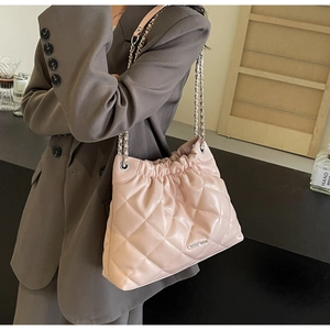 Detailed view of pink quilted bucket bag with silver chain strap and metal logo