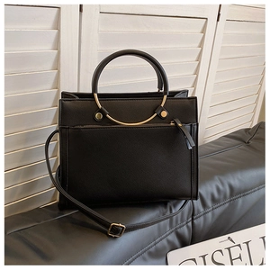 Detail of black pebbled leather tote bag with round gold metal handle and front zipper