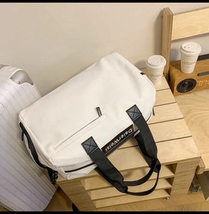 Détail du sac de voyage blanc imperméable avec poignées noires et lettrage de marque