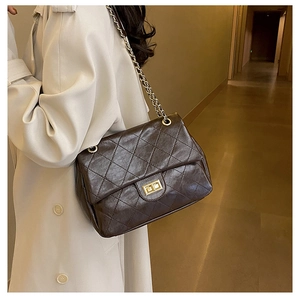 Close-up of brown quilted leather texture and gold chain strap on a designer style bag