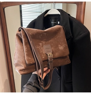 Close-up of vintage brown tote bag with matte faux leather texture and metal buckle detail