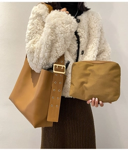 Détail du sac seau en cuir marron avec large bandoulière à œillets et pochette assortie