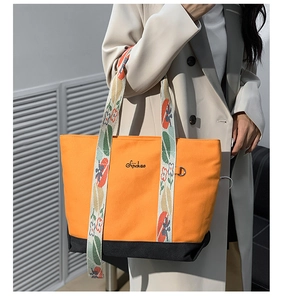 Détail du sac cabas en toile orange avec bandoulière fleurie et broderie